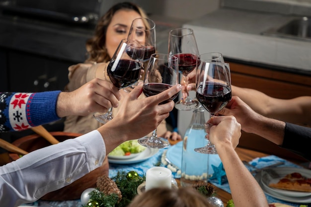 Várias mãos com taças de vinho brindando durante o jantar de natal