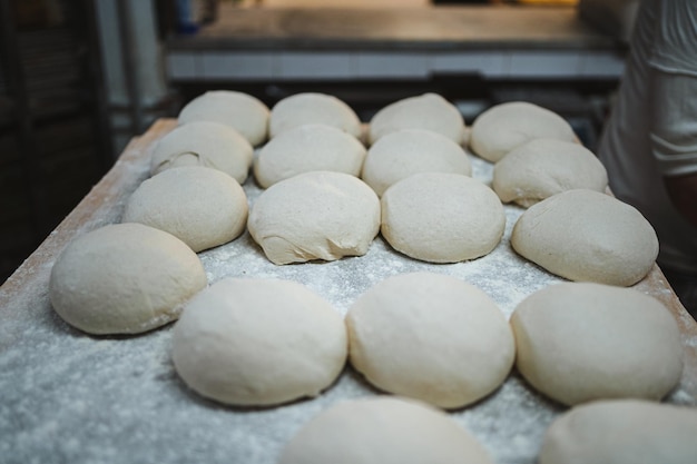 Varias masas de pan de forma redonda en fila descansando a bordo en panadería