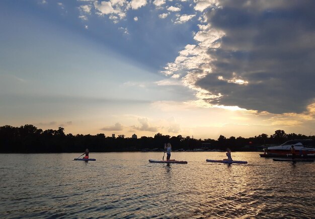 Varias mujeres jóvenes están remando en tablas de paddle SUP contra un hermoso cielo nocturno