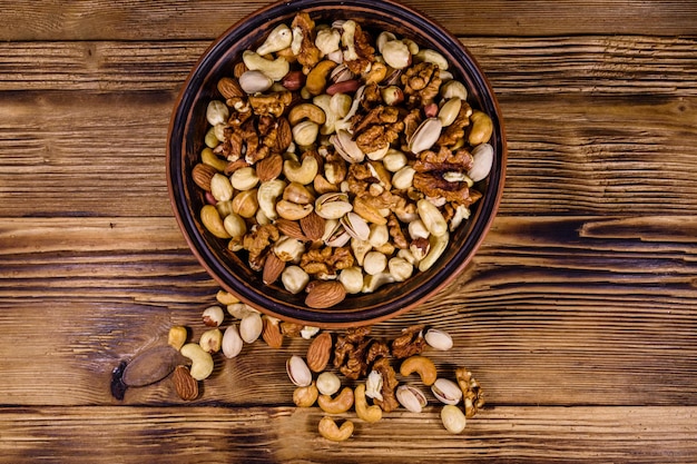 Varias nueces almendra anacardo avellana pistacho nuez en plato de cerámica sobre una mesa de madera Comida vegetariana Concepto de alimentación saludable Vista superior