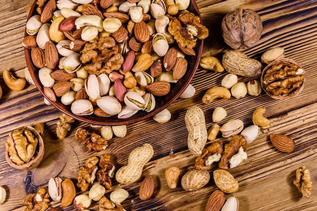 Varias nueces almendra anacardo avellana pistacho nuez en plato de cerámica sobre una mesa de madera Comida vegetariana Concepto de alimentación saludable Vista superior