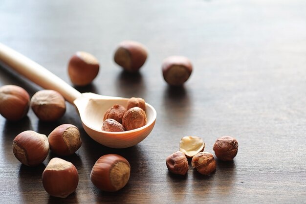 Varias nueces esparcidas y en una cuchara sobre una mesa de textura de madera