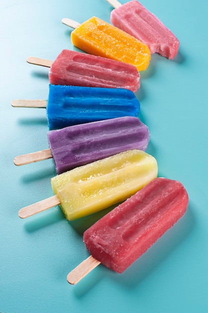 Varias paletas de diferentes sabores juntos sobre un fondo azul.