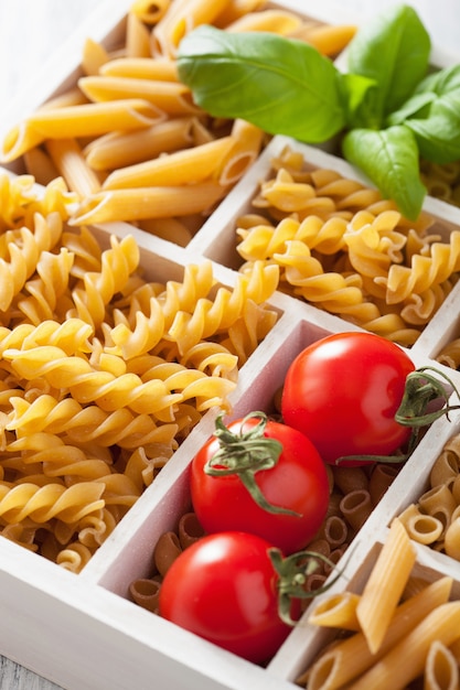 Varias pastas integrales crudas en caja de madera blanca