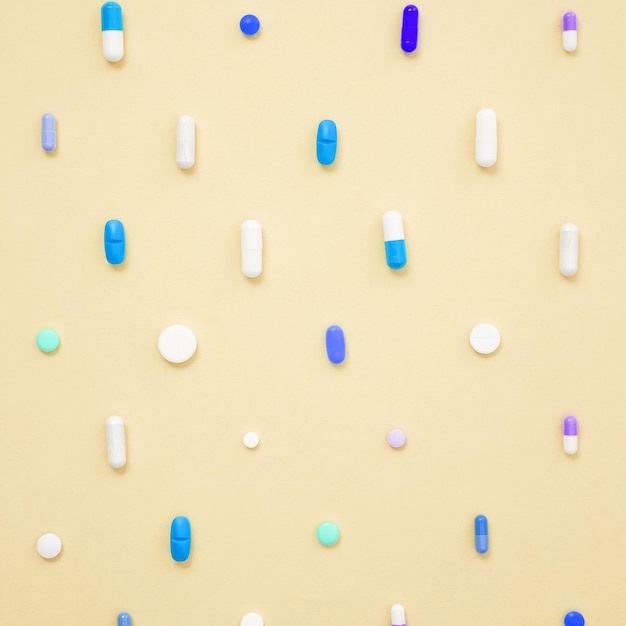 Varias tabletas y cápsulas de medicamentos blancos sobre fondo amarillo Concepto de salud y medicina