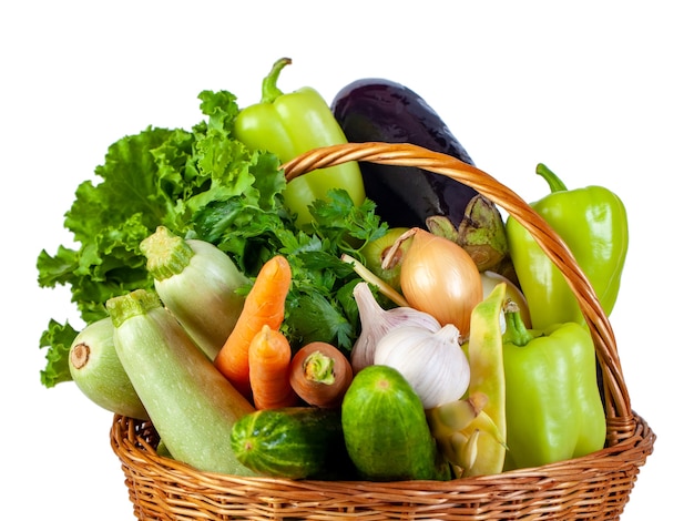 Varias verduras en una cesta de mimbre aislar en blanco, alimentos frescos