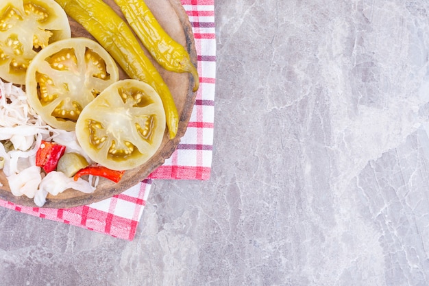 Varias verduras enlatadas en una tabla sobre una toalla, sobre el mármol.