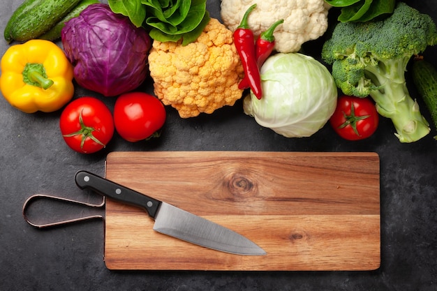 Varias verduras frescas, tabla de cortar y cuchillo.