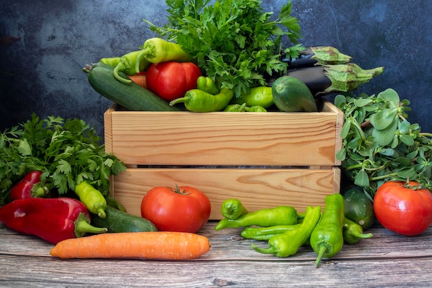 Varias verduras en una mesa de madera Tomate Pimienta verde Pimienta roja perejil zanahoria berenjena pepino