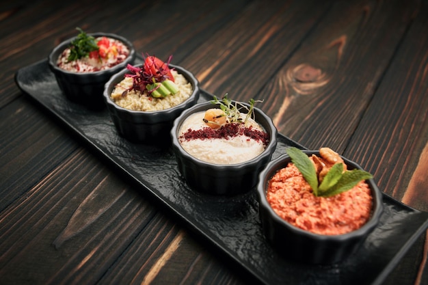 Una variedad de aperitivos vegetales en platos negros sobre un fondo de madera