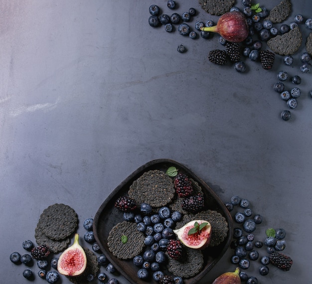 Variedad de bayas e higos con galletas negras.