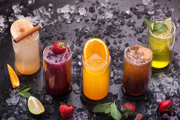 Una variedad de bebidas se alinean en una mesa con hielo y fresas.