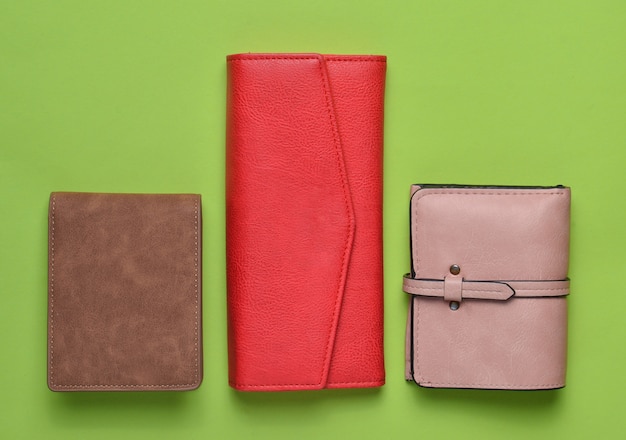 Una variedad de billeteras de cuero para mujer sobre un fondo verde pastel, accesorios para mujer, vista superior, minimalismo