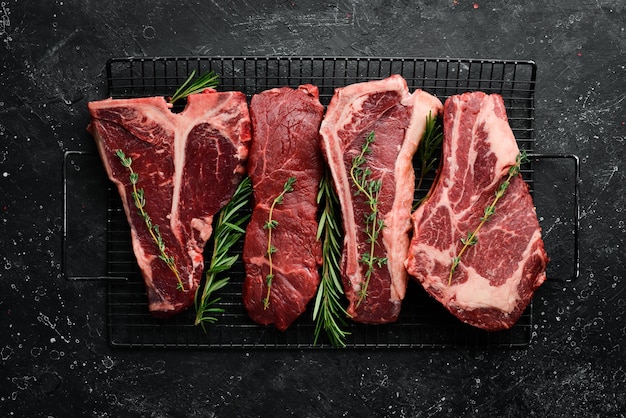 Variedad de bistecs de carne Angus Prime negros crudos tbone striploin Rib eye bistec de nueva york Vista superior sobre un fondo de piedra