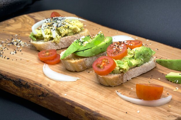 Variedad de bocadillos para aperitivos de desayuno con semillas y tomates sobre tabla de madera