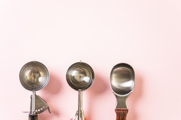 Variedad de bolas de helado de metal vacías sobre fondo rosa.