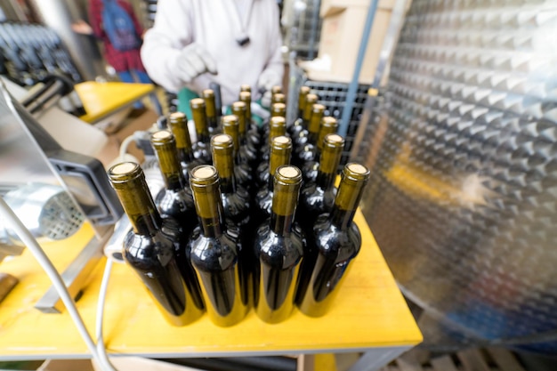 Una variedad de botellas de vino envasadas en la mesa de producción persona que trabaja con botellas