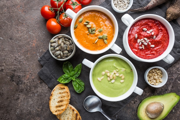 Variedad de diferentes sopas de crema de verduras de colores en cuencos, vista superior. Concepto de alimentación saludable o comida vegetariana.