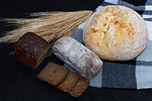 Variedad de diferentes tipos de pan blanco y negro sobre un fondo negro.