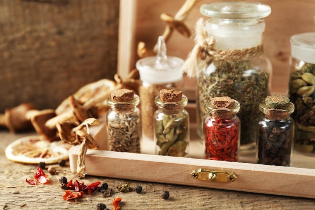 Una variedad de especias en botellas de vidrio sobre fondo de madera