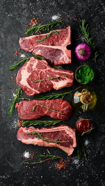 Variedad de filetes de carne cruda Black Angus Prime: t-bone, striploin, Rib eye, new york steak. Vista superior. Sobre un fondo de piedra.