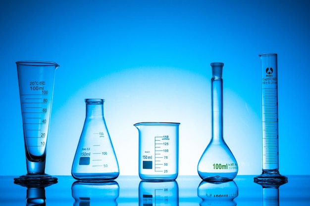 Variedad de frascos de vidrio y equipo de laboratorio sobre un fondo azul.