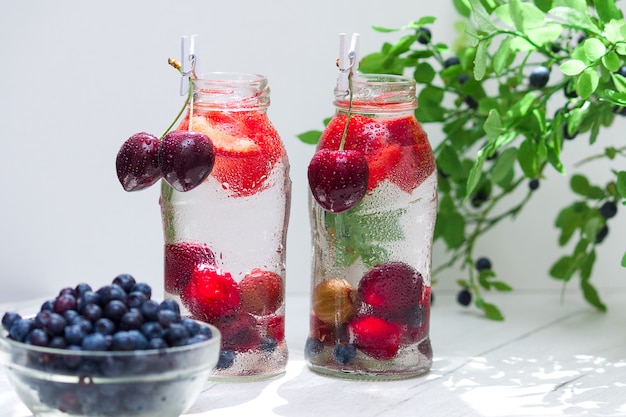 Variedad de frutas con agua detox en botellitas de vidrio. Bebidas refrescantes de verano. Concepto de dieta saludable.