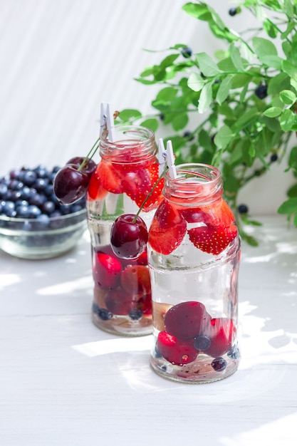 Variedad de frutas con agua detox en botellitas de vidrio. Bebidas refrescantes de verano. Concepto de dieta saludable.