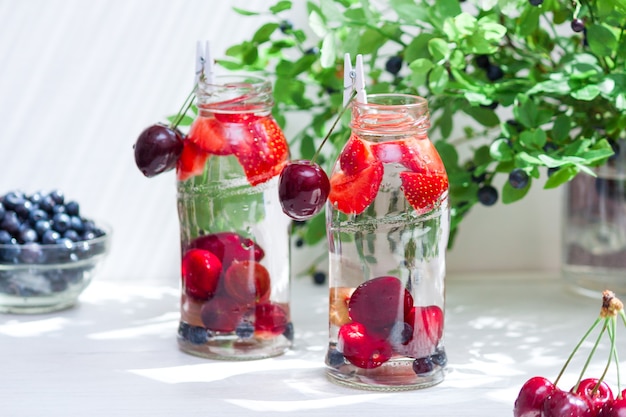 Variedad de frutas con agua detox en botellitas de vidrio. Bebidas refrescantes de verano. Concepto de dieta saludable.