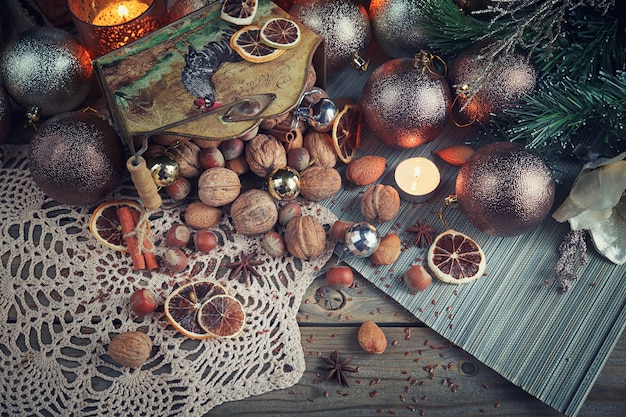 Variedad de frutos secos en decoración navideña y año nuevo. Composición de Navidad y año nuevo con ramas de abeto, velas y luz festiva sobre fondo de madera