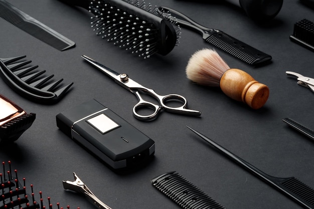 Foto variedad de herramientas y accesorios para peinar el cabello expuestos sobre un fondo oscuro