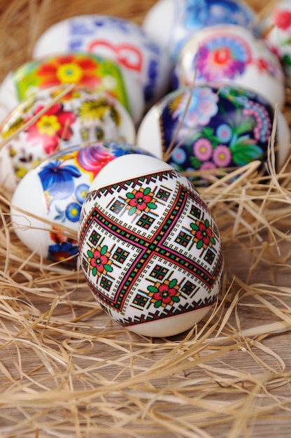 Una variedad de huevos de Pascua pintados sobre la mesa en el heno