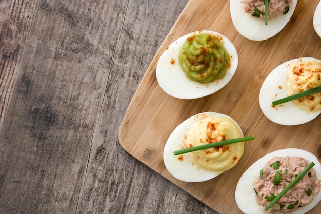 Variedad de huevos rellenos con aguacate y atún en la mesa de madera vista superior espacio de copia