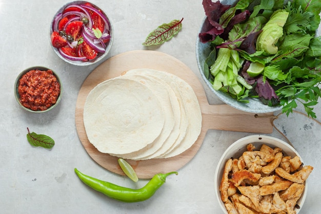 Una variedad de ingredientes que incluyen una tortilla, aguacate y pollo.