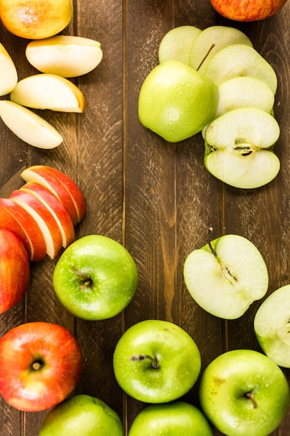 Variedad de manzanas orgánicas en rodajas sobre mesa de madera.