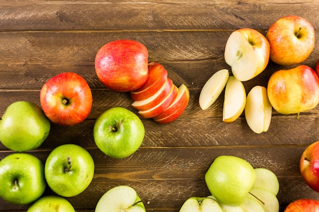 Variedad de manzanas orgánicas en rodajas sobre mesa de madera.