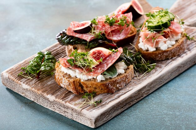 Variedad de mini bocadillos con queso crema, verduras y salami.