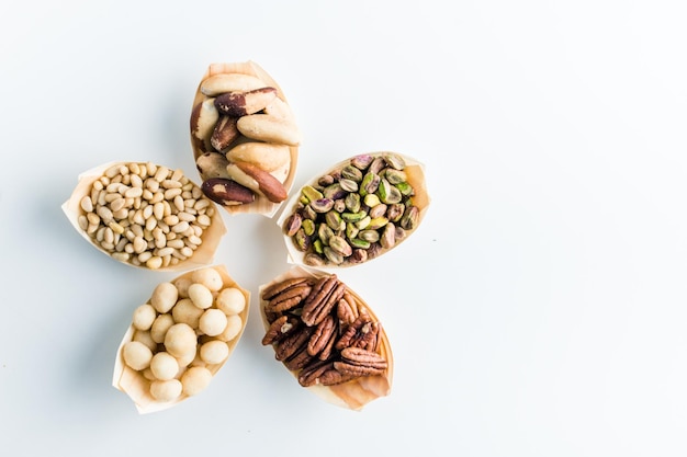 variedad de nueces útiles en tazones de madera sobre un fondo blanco