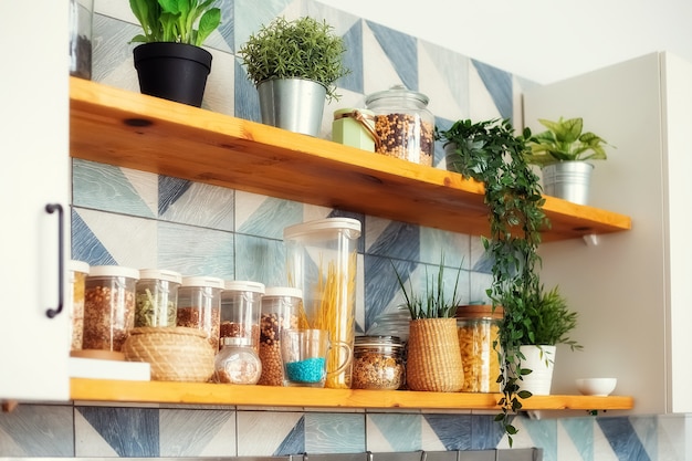 una variedad de pasta en contenedores-latas con productos a granel en los estantes de la cocina luminosa