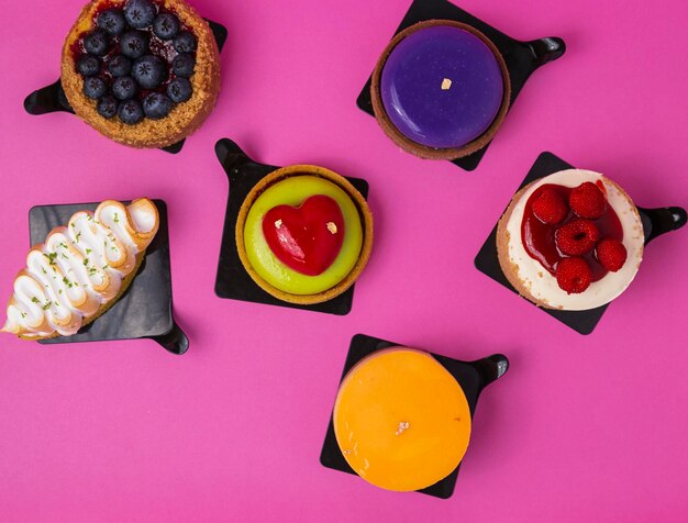 Una variedad de pasteles están sobre un fondo rosa.