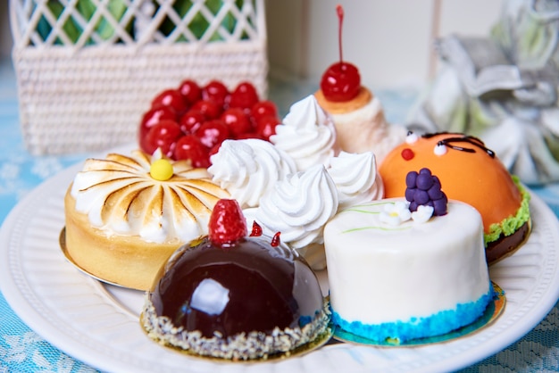 Una variedad de pasteles en un plato blanco de pie sobre una mesa decorada.