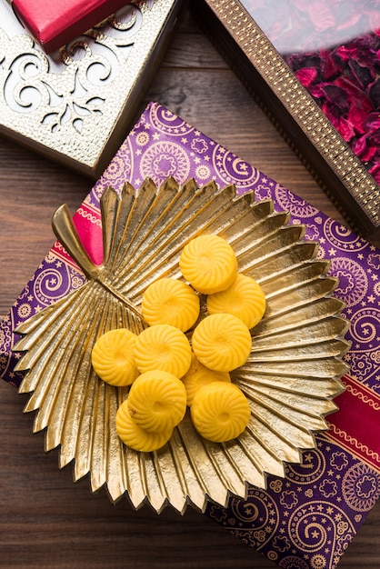 Foto variedad de peda o pedha servido en un cuenco o plato sobre fondo blanco o con montón de regalos. es una comida festiva popular de la india. enfoque selectivo