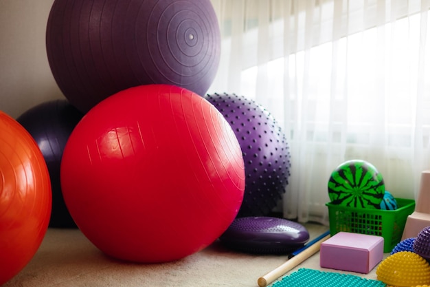 Una variedad de pelotas de ejercicio están sobre una alfombra en una habitación con ventana.