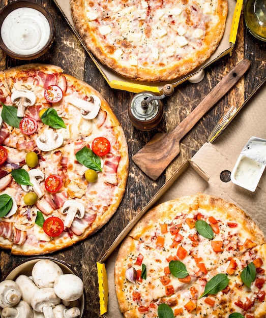 Variedad de pizzas con champiñones y salsa en mesa de madera