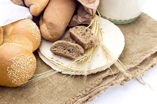 Una variedad de productos de panadería y espiguillas de trigo en un primer plano de fondo blanco