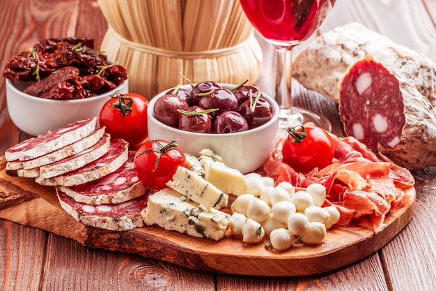 Variedad de queso y carne, aceitunas y tomates en un plato.