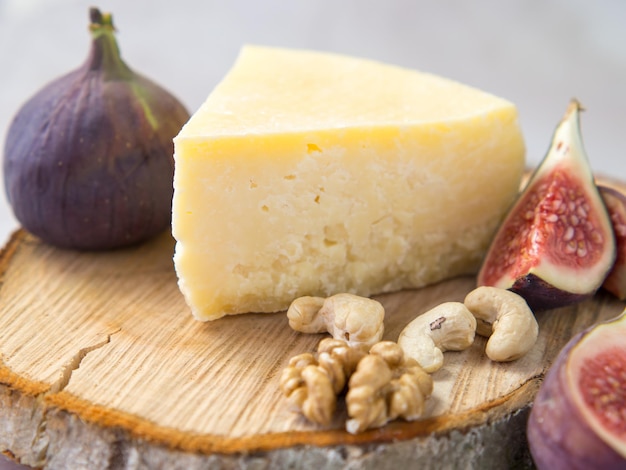 Variedad de queso duro con higos y nueces sobre una tabla de cortar de madera