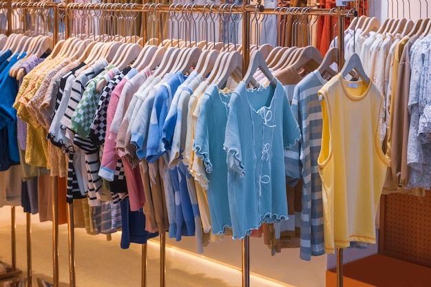 Variedad de ropa para niños colgada en bastidores de ropa a la venta una tienda de moda en un centro comercial | Foto Premium