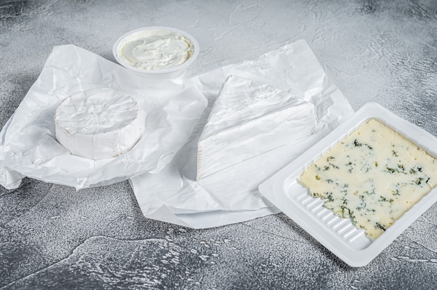 Variedad de tipos de queso en la mesa de la cocina, brie, camembert, gorgonzola y queso cremoso azul.