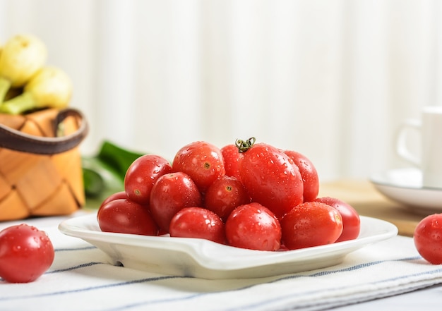 Variedad de tomates en una bandeja artesanal con vista lateral de lechuga en madera